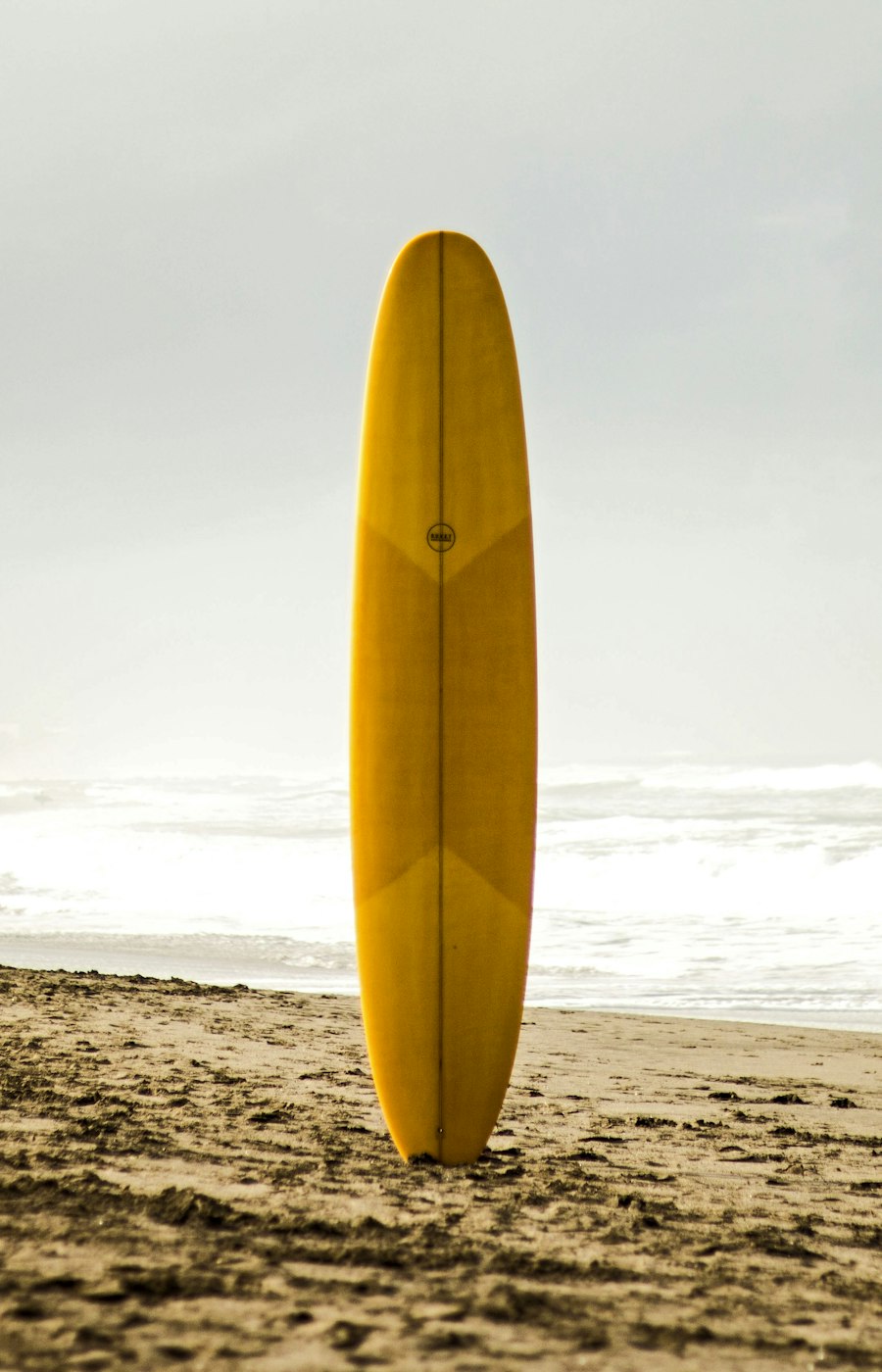 Planche de surf plantée dans le sable au bord de l'océan