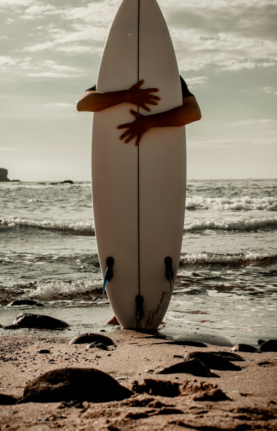 Surfeur tenant une planche blanche face à l'océan